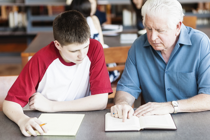 Senior man tutoring a teenager in the library